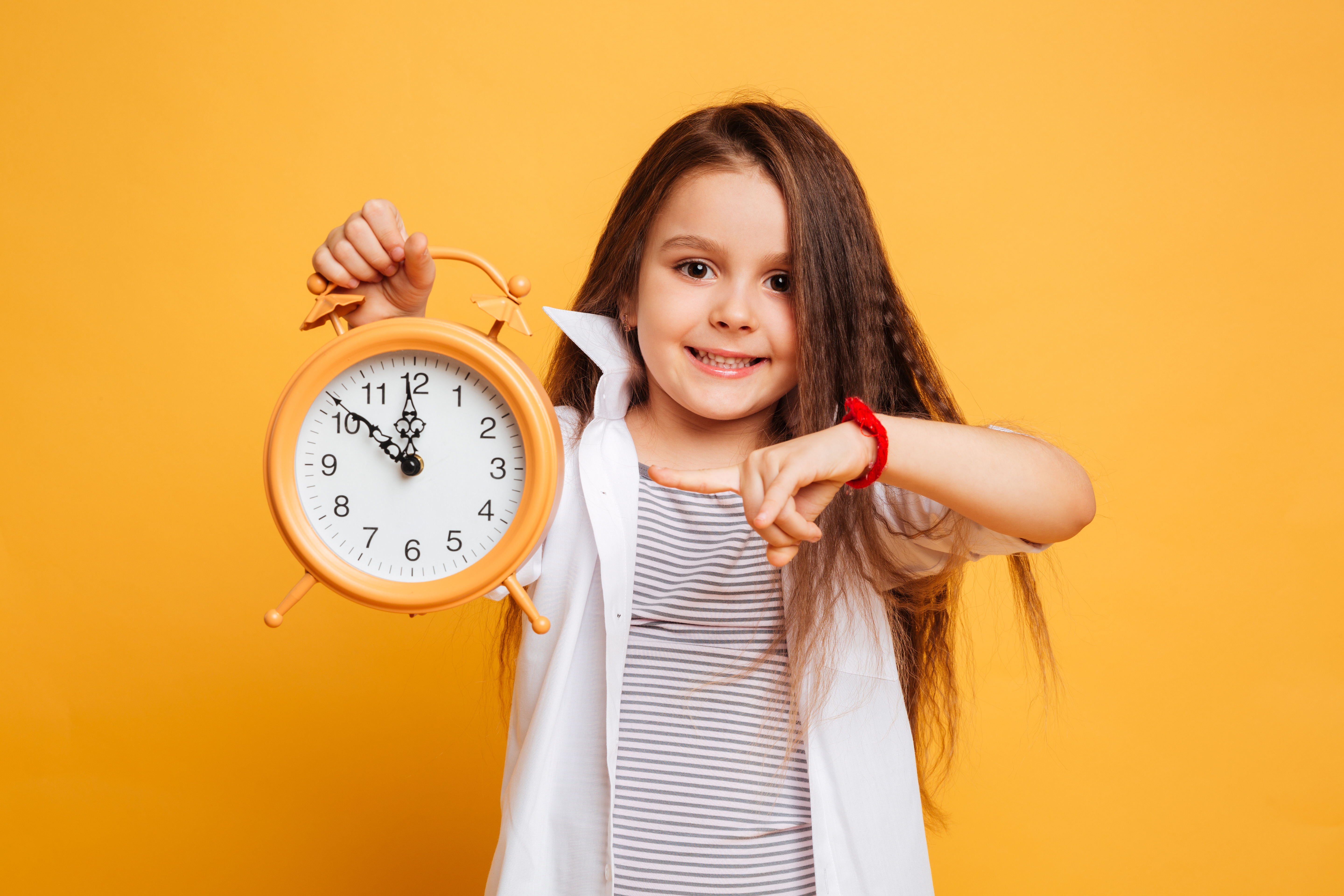Child holding clock with orange background